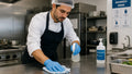 Un addetto in cucina professionale sanifica una superficie di lavoro